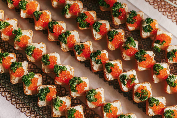 istock Delicious finger appetizers table at wedding reception. Caviar on bread canapes row top view on table at wedding or christmas feast. Luxury catering concept. Seafood flat lay 1159174374
