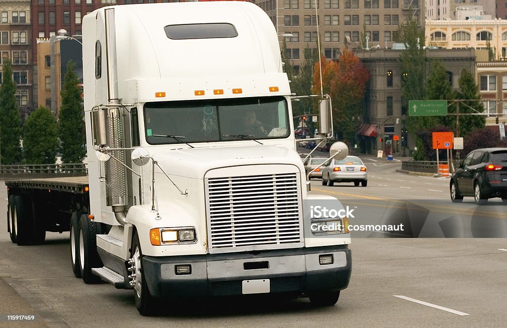 Flatbed Semi Truck on a City Street A flatbed truck heads out of donwtown Portland on the Morrison Bridge. Struggle Stock Photo