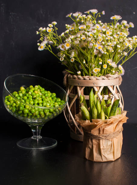 Beautiful summer still life with green peas and wild flowers