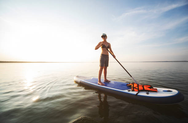 istock Young adult woman paddle boarding 1159175435
