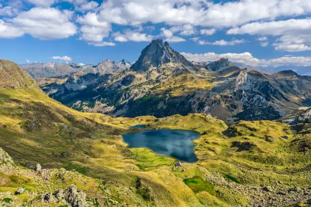 View at Ossau valley from the mountain pass Ayous in Franch Atlantic Pyrenees, as seen in October. Lake Gentau is at foreground of the famous Pyrenean peak Midi Ossau.