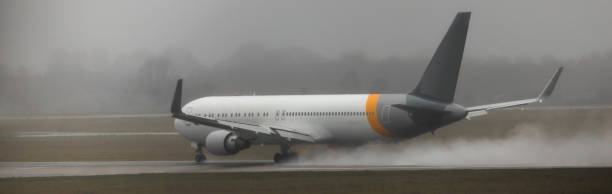 un aereo che accelera su una pista bagnata - runway airport rain wet foto e immagini stock