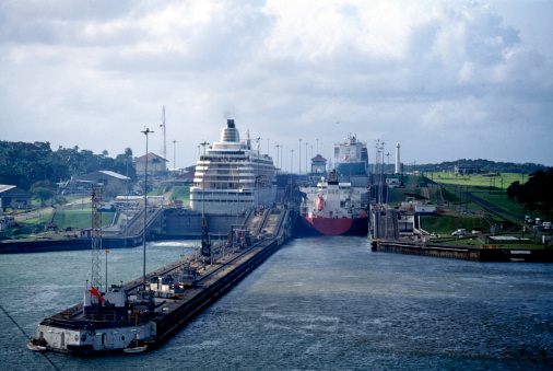 Three ships in Gatun Locks, one at each of the three levels used to raise ships from the Atlantic Ocean into Gatun Lake which crosses Panama. The farthest ship is a container ship, near right a tanker and left a cruise ship. Haze around ships is caused by diesel exhaust from ships' engines.