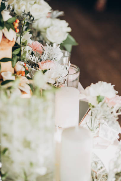istock Stylish floral decor on wedding table. White roses ,eustoma, candle,  hydrangea flowers in glass  on wedding centerpiece. Luxury catering and adorning 1159179325