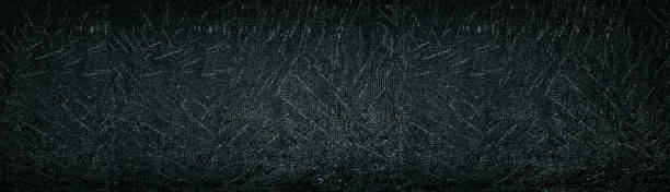 istock Black old stamped concrete wall wide panoramic background. Dark aged cement surface texture 1159179553
