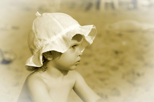 Little baby on the beach. Sepia. White vignette.