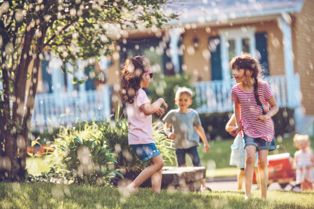 istock Happy kids playing with garden sprinkler 1159179779