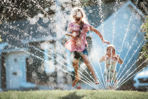 istock Happy kids playing with garden sprinkler 1159179804
