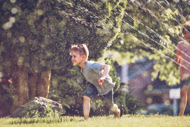 istock Happy kids playing with garden sprinkler 1159180350