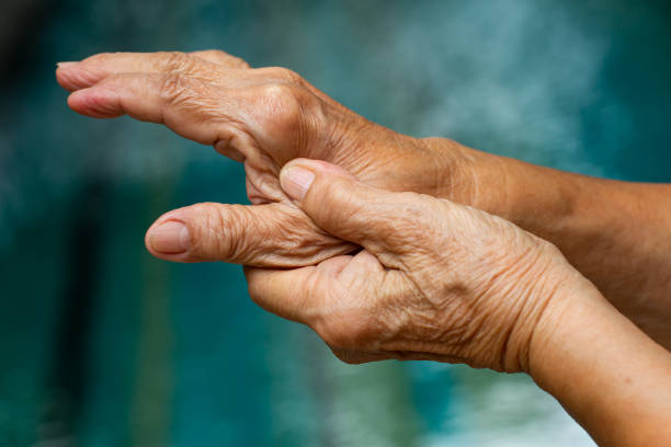 trigger finger, la mano sinistra della donna anziana che massaggia il dito del pollice, soffre di dolore, close up & macro shot, sfondo piscina, sindrome dell'ufficio, sanità e massaggio concetto di corpo asiatico - arthritis foto e immagini stock