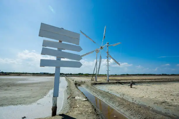 Blank white wooden guidepost on salt lake with wind propelled. blank wooden sign painted using white color, blue sky background.