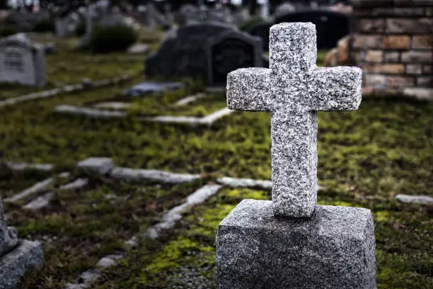 Photo of Tombstone cross in a cemetery, other graves in the background