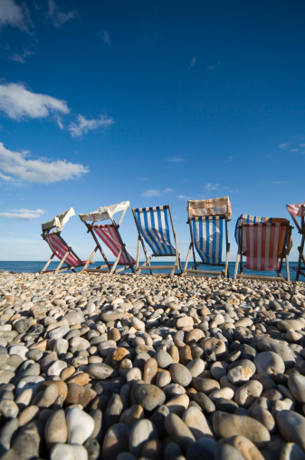 colourful striped deck chairs on a pebbled beach; Beer, United Kingdom