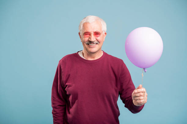 istock Happy retired man in pullover and eyeglasses holding balloon 1159183881