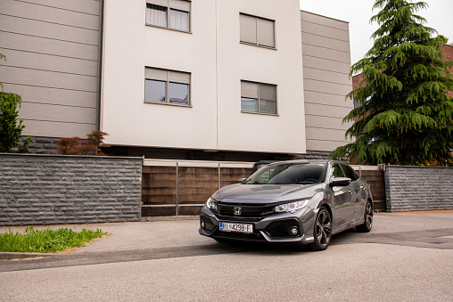Zagreb, Croatia - May 12, 2019: New Honda Civic in grey colour in front of the house. New Honda model. Front view of the car.