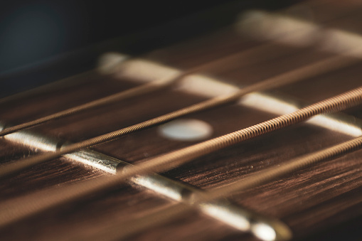 Macro close up shot of acoustic guitar strings on sun shine. Music and guitar playing concept toned