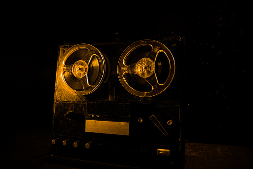 Old vintage reel to reel player and recorder on dark toned foggy background. Analog Stereo Open Reel Tape Deck Recorder Player with Reels. Selective focus