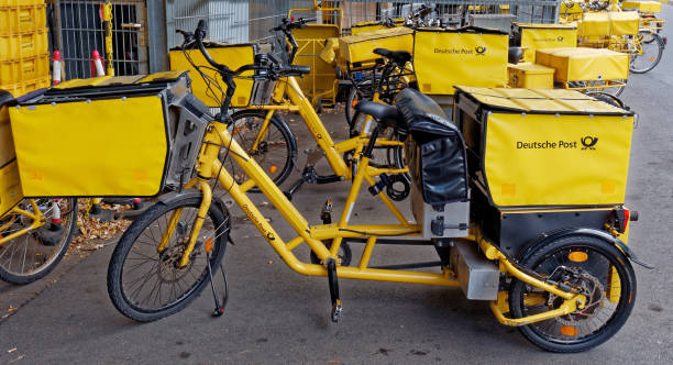 cargo tricycle of Deutsche Post Fuerth, Germany - October 3, 2018: Detail view of the yellow tricycles of Deutsche Post AG with bike bags and containers standing after work and waiting for the next use. The tricycle has an electric drive. fuerth stock pictures, royalty-free photos & images