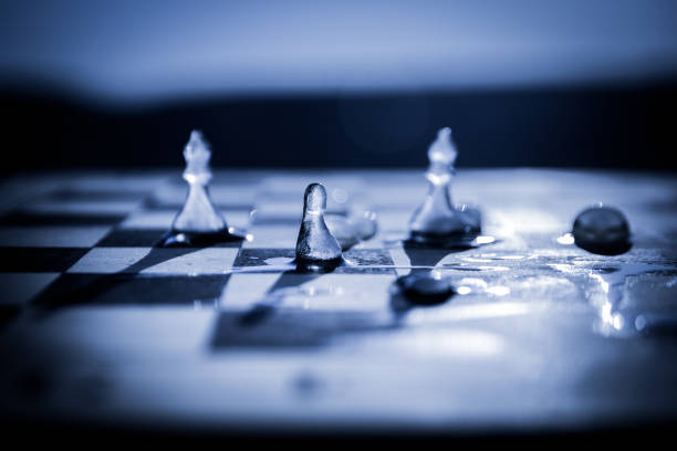 Strategy and tactics concept. Icy frosted chess figures standing on a chessboard during sunset. Melting ice chess