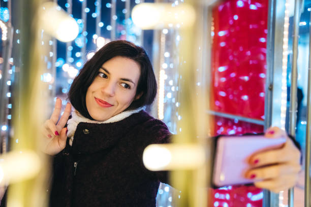 istock Woman making selfie among Christmas string lights 1159199272