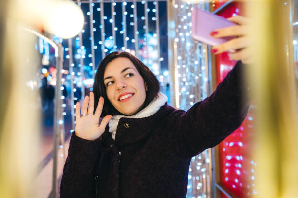 istock Woman making selfie among Christmas string lights 1159199851