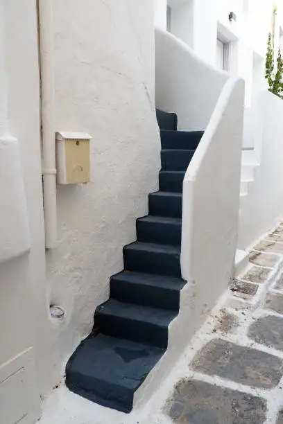 Photo of One of the charms of Mykonos, Greek island in the heart of the Cyclades, are its narrow staircases to access white houses with small flowered balconies touching almost above the cobblestone streets
