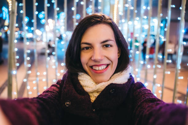 istock Woman making selfie among Christmas string lights 1159200177