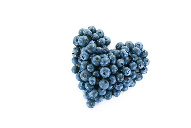 Pile of delicious blueberries formed into heart shape on white