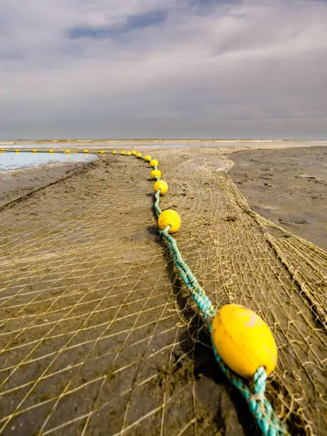 Photo of Closeup of a fishnet at the beach waiting for high tide