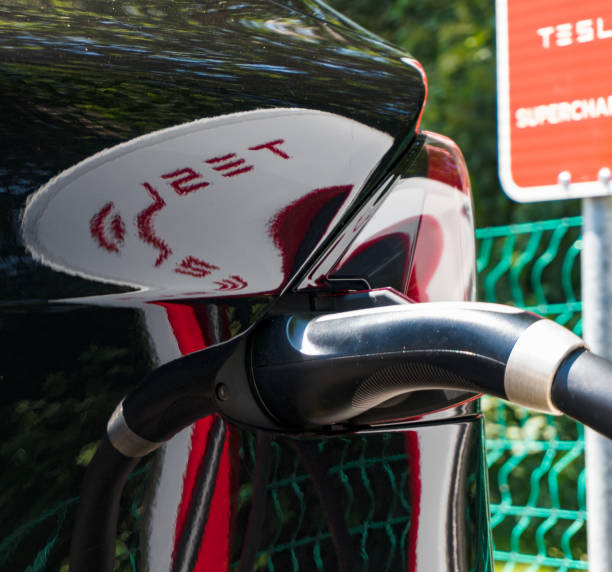 detail of a Tesla car charging at the Tesla Super Charging Station in Maienfeld with reflections of charging station Maienfeld, GR / Switzerland - 30 June, 2019: detail of a Tesla car charging at the Tesla Super Charging Station in Maienfeld  with reflections of supercharger station elon musk stock pictures, royalty-free photos & images