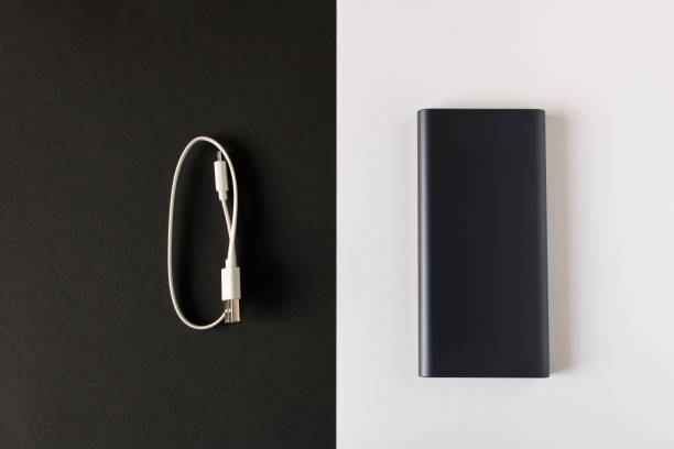 istock Black power Bank with adapter for charging mobile devices on a black white background. 1159202898