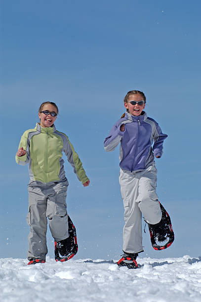 bambini con le racchette da neve contro il cielo blu - winter snowshoeing running snowshoe foto e immagini stock