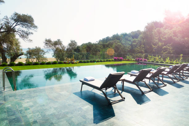 istock Deck chairs on plank floor against swimming pool 1159204248