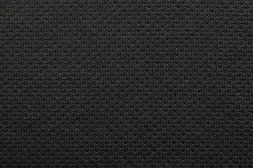 Close-up polyester fabric texture of black athletic shirt with ambient light