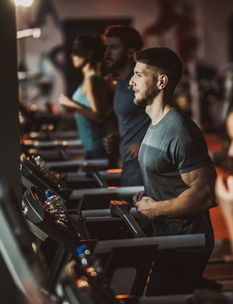 istock Athletic man running on treadmill during sports training in a gym. 1159211447