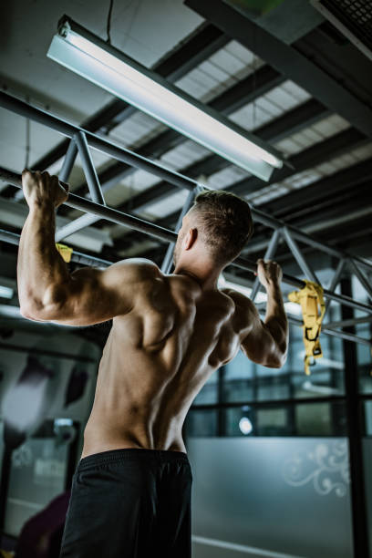 istock Rear view of athletic man exercising pull-ups in a gym. 1159211557