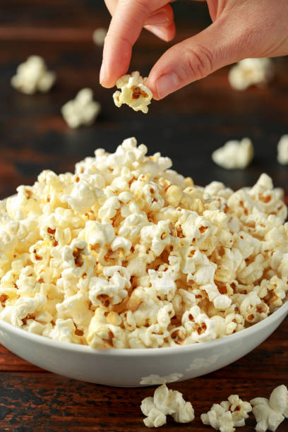 istock Hand takes salty popcorn from the bowl 1159212472