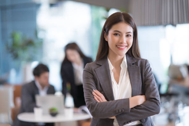 Portrait of successful young Asian businesswomanÂ at office, colleagues in background. stock photo