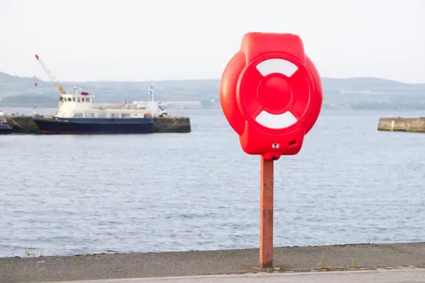 Red ring for water safety at sea dock and ships in background uk