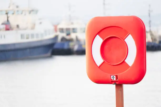 Red ring for water safety at sea dock and ships in background uk