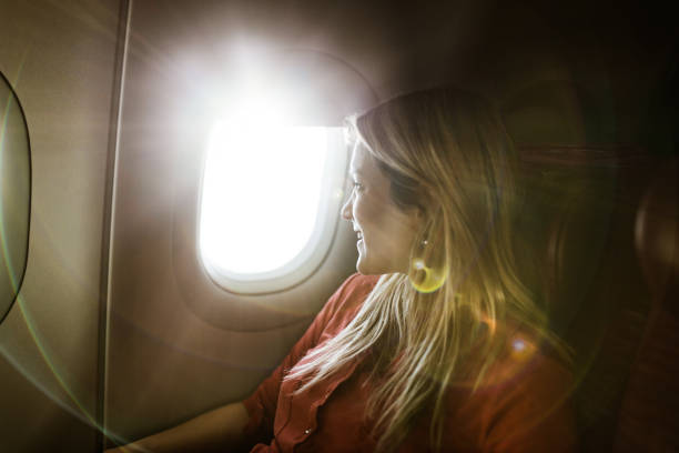 istock Young happy woman looking through window during her flight by plane. 1159215885