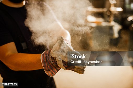 istock Close up of unrecognizable worker cleaning dust from his gloves. 1159217863