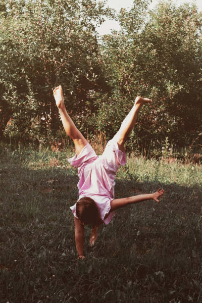 istock Young girl in pink clothes is standing upside down 1159219551