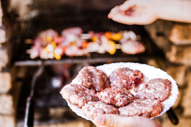 Close up of unrecognizable person holding plate with ground beef for barbecue.