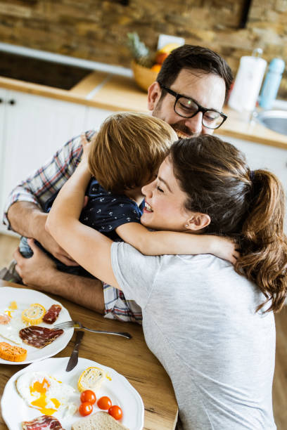 istock Young happy family embracing during breakfast at dining table. 1159220041