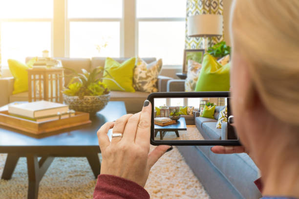 mujer tomando fotos de una sala de estar en la casa modelo con su teléfono inteligente - hacer fotos fotografías e imágenes de stock