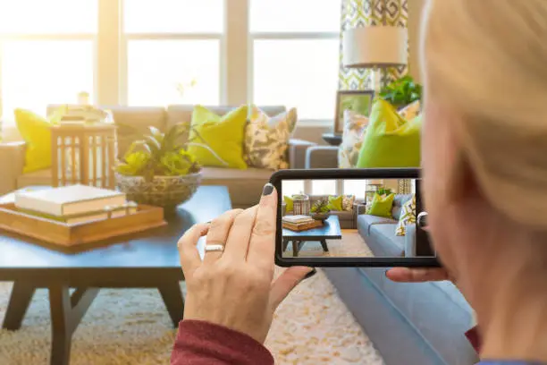 Woman Taking Pictures of A Living Room in Model Home with Her Smart Phone.