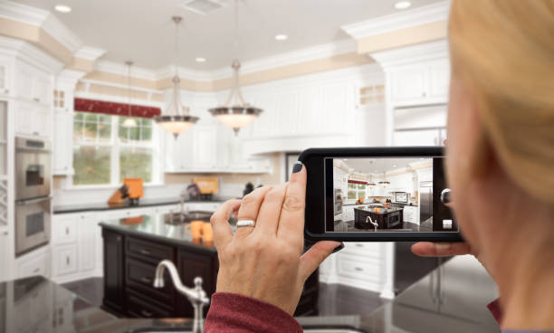 mujer tomando fotos de una cocina personalizada con su teléfono inteligente - casa fotos fotografías e imágenes de stock
