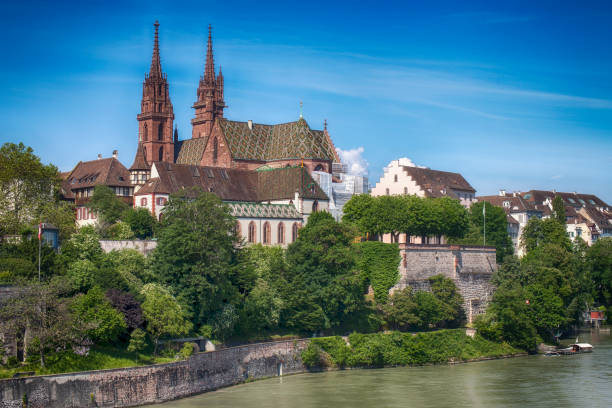 St. Martin’s Church rises proudly above the city as the morning sun casts a golden glow across Basel’s skyline. The calm Rhine River flows beneath, reflecting the light, while Mittlere Rheinbrücke connects the city’s vibrant past and present in this stunning aerial view.