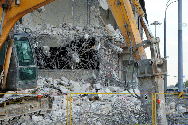 istock An excavator demolishes a multi-storey building with a chisel tool. Technique destroys the building, hanging fixtures, concrete and stones. The fence of the yellow fence. 1159223872